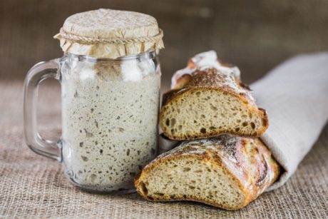 a sourdough bread alongside a jar of sourdough, showcasing the art of sourdough baking class