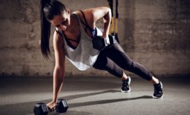 woman doing plank while holding dumbbells