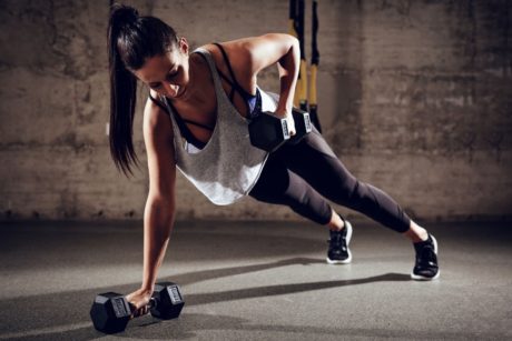 woman doing plank while holding dumbbells