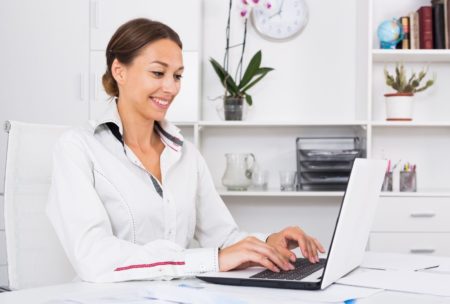 woman typing on white laptop