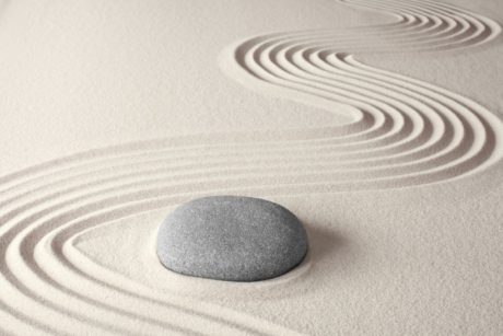a serene stone rests on sandy ground in a zen garden, embodying the essence of a tranquil zen lifestyle