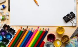 an open notebook surrounded by a pencil, paint, and various art supplies for a drawing masterclass