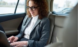 female entrepreneur working on laptop while riding in car