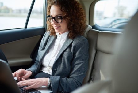 female entrepreneur working on laptop while riding in car