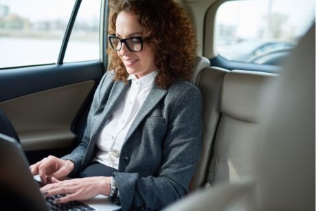 female entrepreneur working on laptop while riding in car