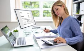 woman using calculator and excel on computer