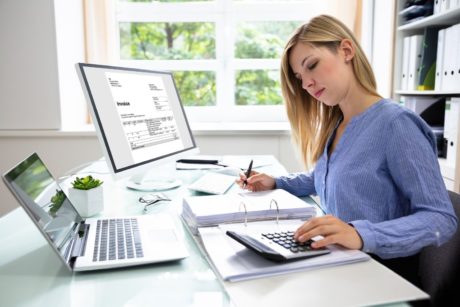 woman using calculator and excel on computer