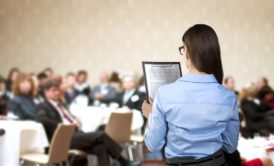 woman speaking in front of large audience