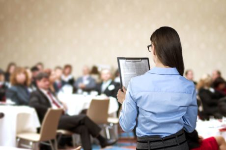 woman speaking in front of large audience