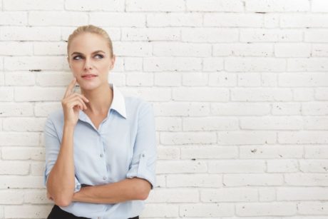 woman leaning on white wall thinking