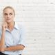 woman leaning on white wall thinking
