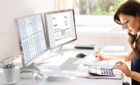 woman using calculator and quickbooks on computer