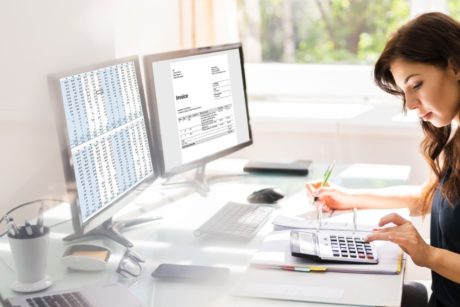 woman using calculator and quickbooks on computer