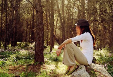 woman sitting on top of big rock