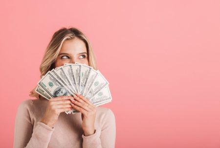 woman in pink sweater holding paper bills