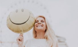 woman holding a smiley balloon