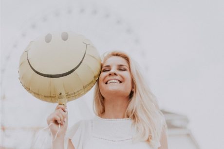 woman holding a smiley balloon