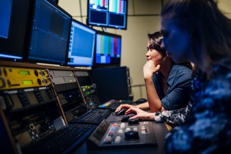 two people editing a broadcast using adobe premiere