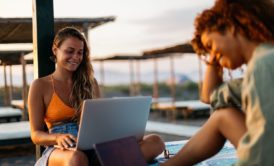 female digital nomad in orange bikini working while on vacation