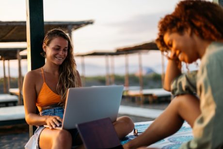 female digital nomad in orange bikini working while on vacation