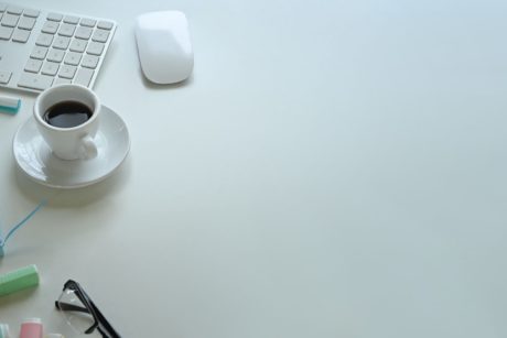 white keyboard mouse and a cup of coffee on white desk