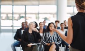 female speaker with eloquent body language talking to a group of people