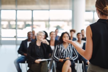 female speaker with eloquent body language talking to a group of people