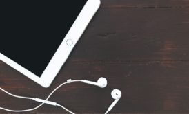 white ipad and earphones on brown tabletop