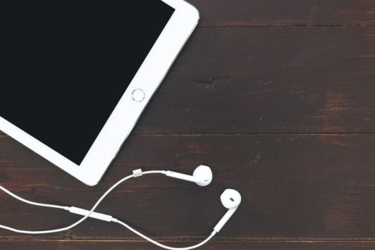 white ipad and earphones on brown tabletop