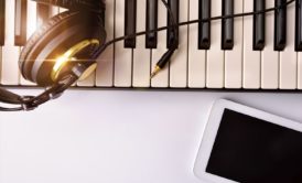 electronic keyboard headphones and white smartphone on white table top