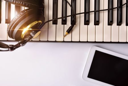 electronic keyboard headphones and white smartphone on white table top