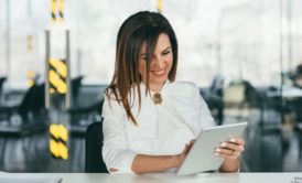 successful woman in white suit smiling and using ipad