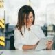 successful woman in white suit smiling and using ipad