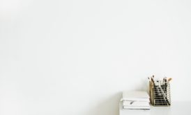 white desk with a notebook against a white wall