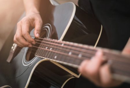 man playing black acoustic guitar