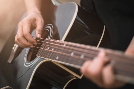 man playing black acoustic guitar