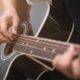 man playing black acoustic guitar