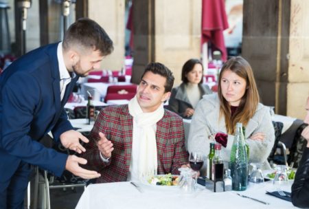 waiter in blue suit dealing with two angry customers