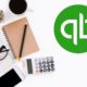 quickbooks logo laptop notebook calculator and mobile phone on white desk