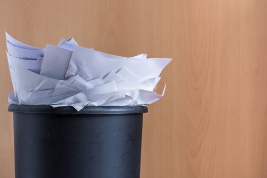 a pile of paper inside a black trash can