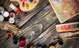acrylic paints and palettes on wooden floor