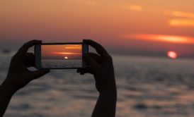 person taking photo of sunset using mobile phone