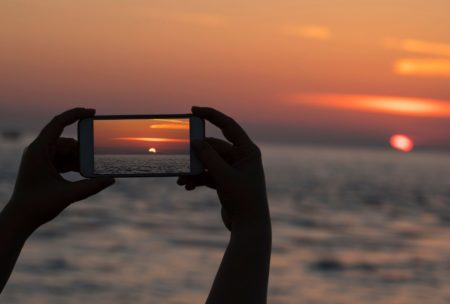 person taking photo of sunset using mobile phone