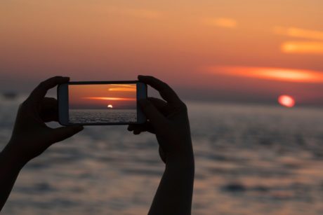 person taking photo of sunset using mobile phone