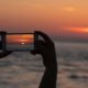 person taking photo of sunset using mobile phone