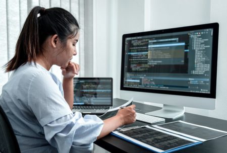 female javascript developer coding on white desktop computer