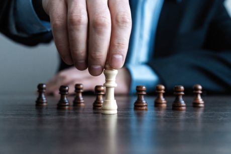 man holding a white king chess piece