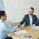 two men shaking hands in a corporate boardroom