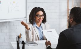 female applicant in white suit talking to a male interviewer