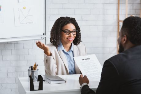 female applicant in white suit talking to a male interviewer